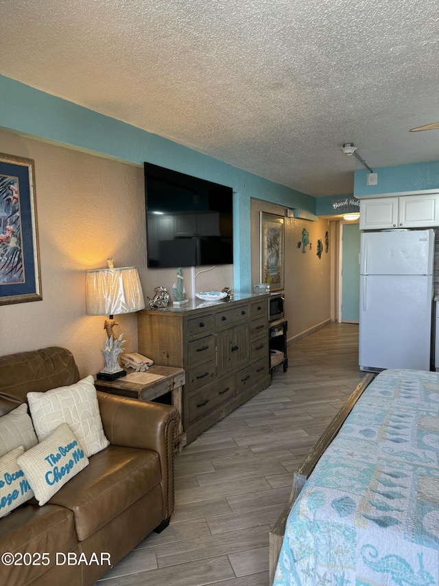 bedroom featuring light wood-type flooring, a textured ceiling, and white refrigerator