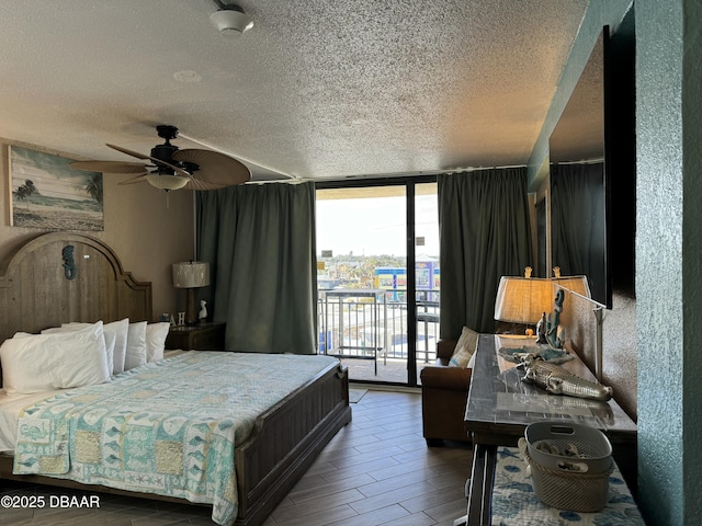 bedroom with a textured ceiling, a wall of windows, wood-type flooring, and access to outside