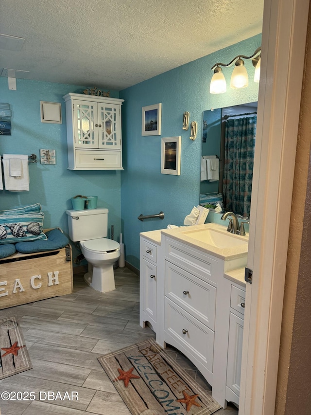 bathroom featuring vanity, a textured ceiling, and toilet