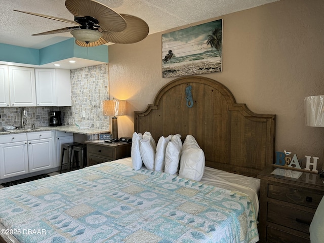 bedroom with ceiling fan, sink, and a textured ceiling