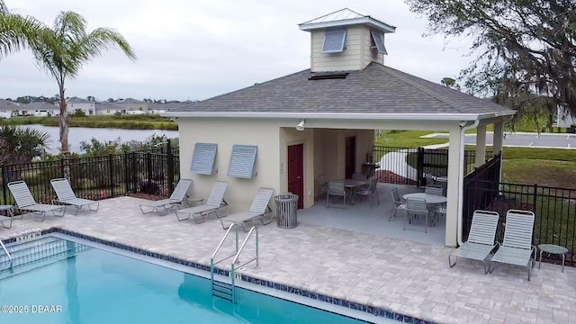 back of property with a water view, a community pool, and a patio area