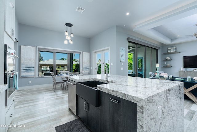 kitchen featuring french doors, sink, pendant lighting, light wood-type flooring, and a large island with sink