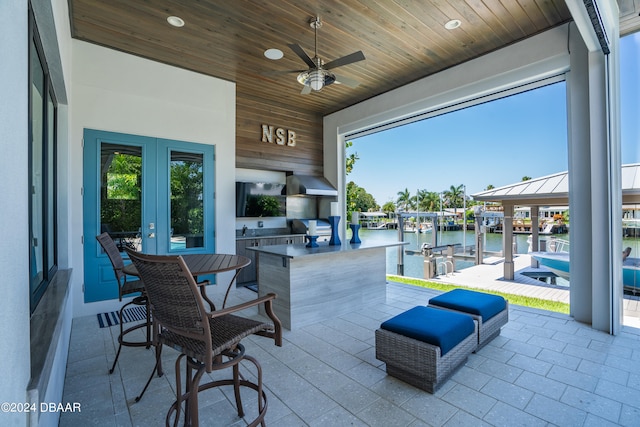 view of patio featuring an outdoor kitchen, ceiling fan, a grill, and a water view