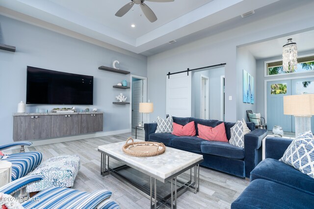 living room with light wood-type flooring, a barn door, and ceiling fan