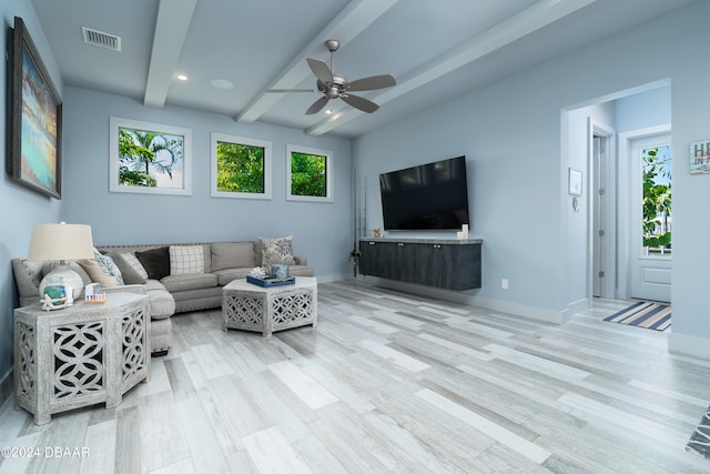 living room featuring beamed ceiling, a healthy amount of sunlight, and light wood-type flooring