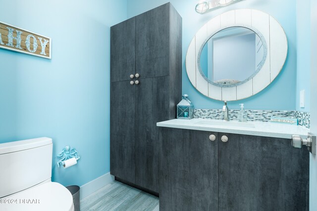 bathroom with toilet, backsplash, vanity, and hardwood / wood-style floors