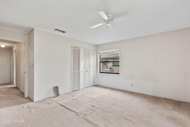 unfurnished bedroom featuring a textured ceiling, carpet floors, a closet, and visible vents