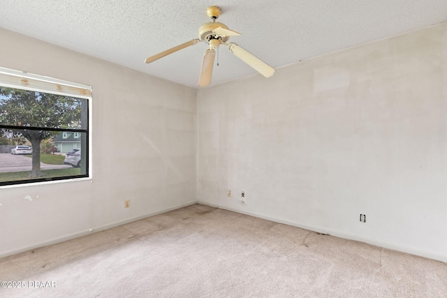 unfurnished room featuring a textured ceiling, carpet, a ceiling fan, and baseboards