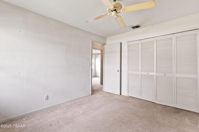 unfurnished bedroom with visible vents, ceiling fan, carpet, a textured ceiling, and a closet