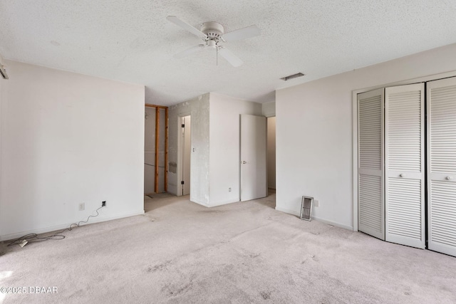 unfurnished bedroom with baseboards, visible vents, a textured ceiling, carpet flooring, and a closet