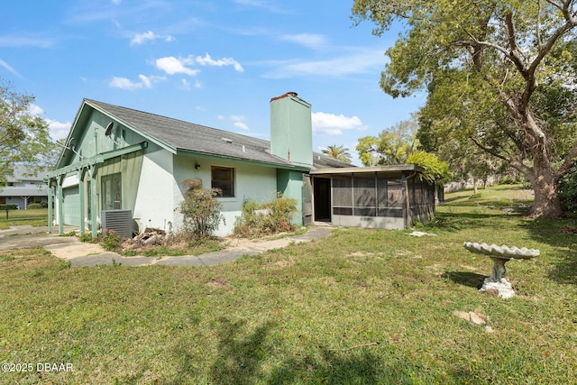 back of property featuring a yard, a chimney, and a sunroom