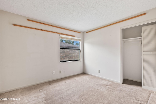 unfurnished bedroom featuring a textured ceiling, carpet floors, a closet, and baseboards