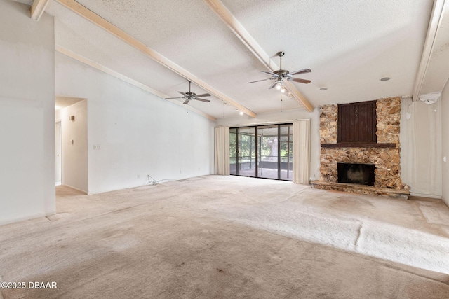 unfurnished living room featuring beam ceiling, light carpet, ceiling fan, a textured ceiling, and a stone fireplace