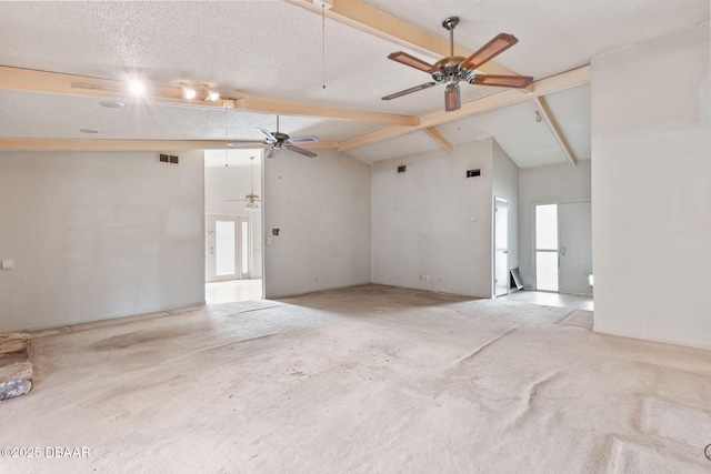 spare room featuring a wealth of natural light, a textured ceiling, visible vents, and beam ceiling