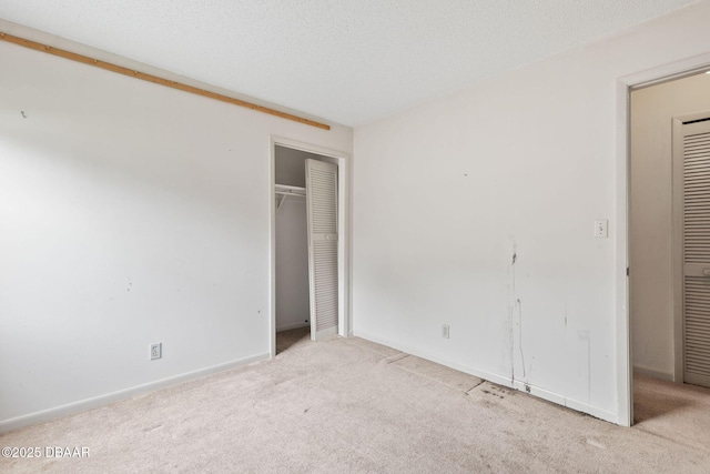 unfurnished bedroom featuring a textured ceiling, carpet floors, a closet, and baseboards