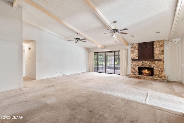 unfurnished living room with ceiling fan, beamed ceiling, a textured ceiling, carpet flooring, and a fireplace