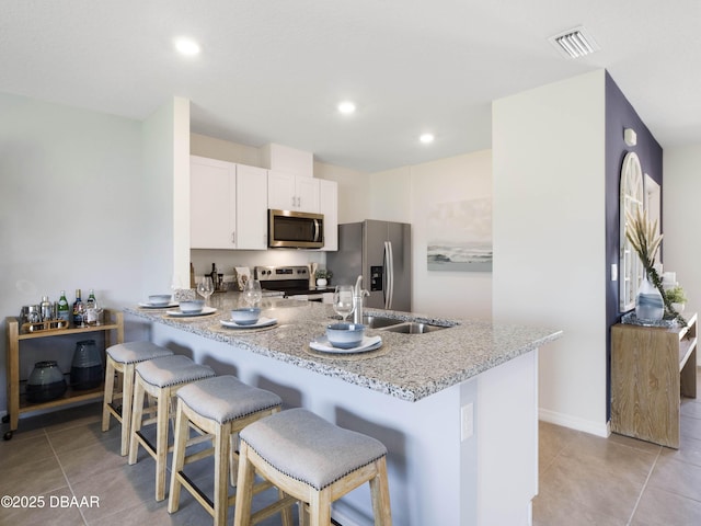 kitchen with sink, white cabinetry, appliances with stainless steel finishes, a kitchen breakfast bar, and kitchen peninsula