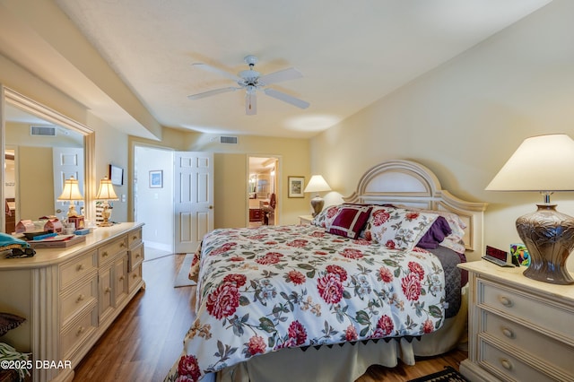 bedroom with dark wood-type flooring, ceiling fan, and ensuite bathroom