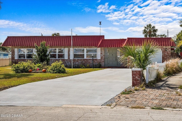 view of front of property featuring brick siding, fence, driveway, and a front lawn