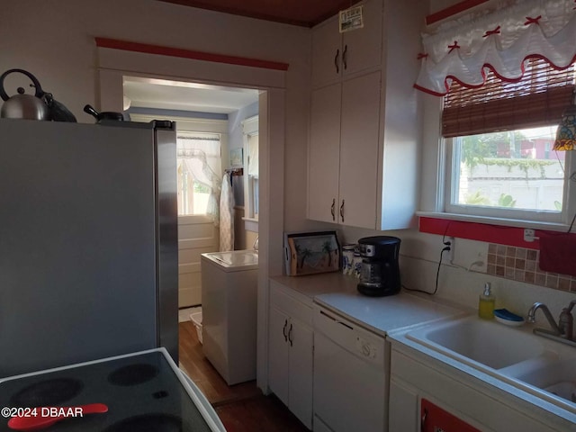 kitchen featuring stainless steel fridge, white cabinetry, sink, and a wealth of natural light