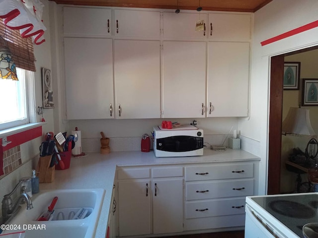 kitchen featuring white appliances, backsplash, white cabinetry, and sink