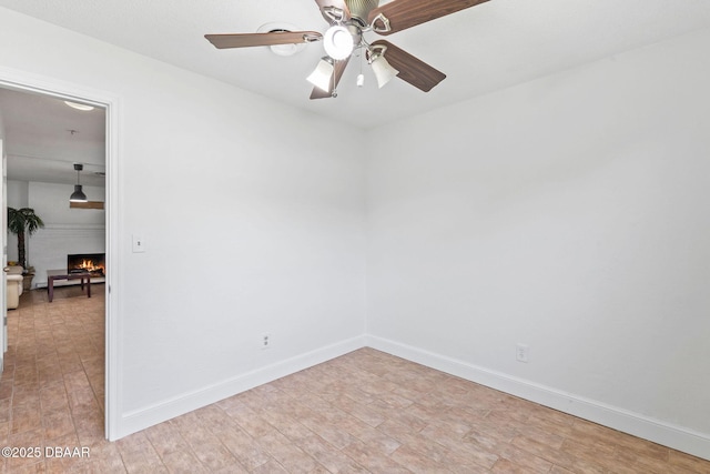 321 Scotland Dr, Holly Hill, FL 32117 - unfurnished room with ceiling fan, a warm lit fireplace, light wood-type flooring, and baseboards