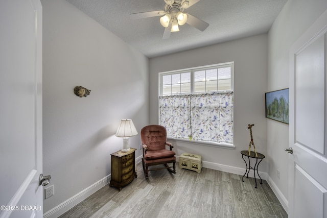 living area with a ceiling fan, baseboards, and wood finished floors