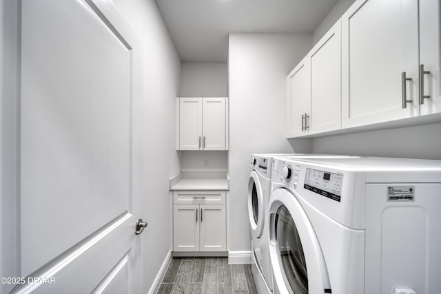 washroom featuring baseboards, washer and clothes dryer, cabinet space, and light wood-style flooring