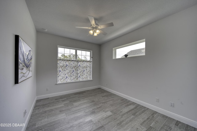 empty room featuring baseboards, ceiling fan, a textured ceiling, and wood finished floors