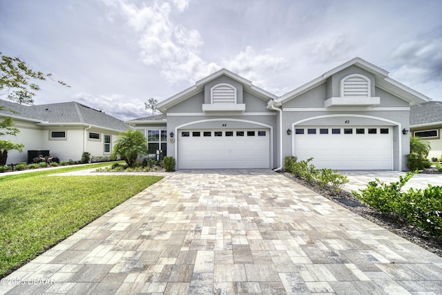 view of front of house featuring stucco siding, decorative driveway, a garage, and a front lawn