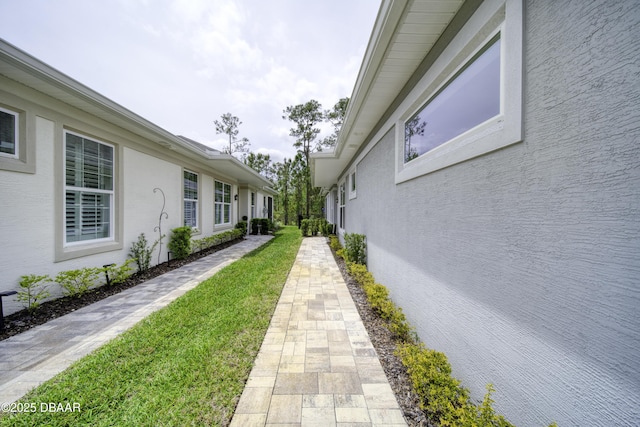 view of side of home featuring stucco siding and a yard