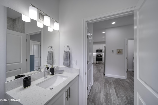bathroom with recessed lighting, baseboards, wood finished floors, and vanity