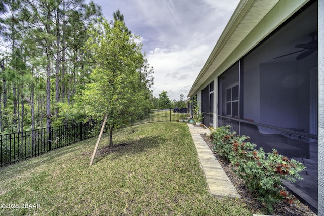 view of yard featuring a fenced backyard, ceiling fan, and a sunroom