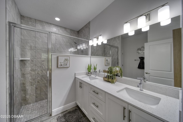 bathroom with a sink, a shower stall, and double vanity