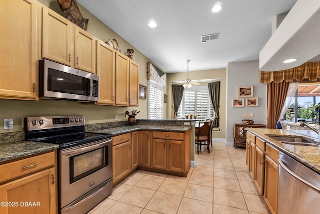 4 Arika At Lionspaw, Daytona Beach, FL 32124 - kitchen featuring stainless steel appliances, a peninsula, dark stone countertops, light tile patterned floors, and ceiling fan