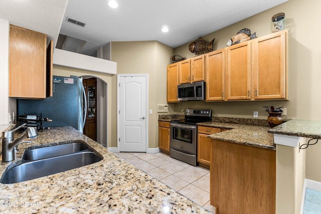 4 Arika At Lionspaw, Daytona Beach, FL 32124 - kitchen with appliances with stainless steel finishes, a peninsula, light tile patterned flooring, arched walkways, and dark stone countertops