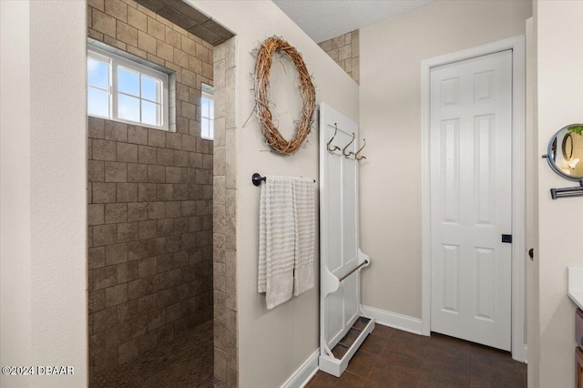 bathroom featuring tile patterned flooring, vanity, and tiled shower