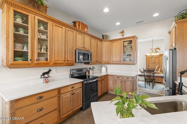 kitchen featuring appliances with stainless steel finishes, a textured ceiling, decorative light fixtures, and an inviting chandelier