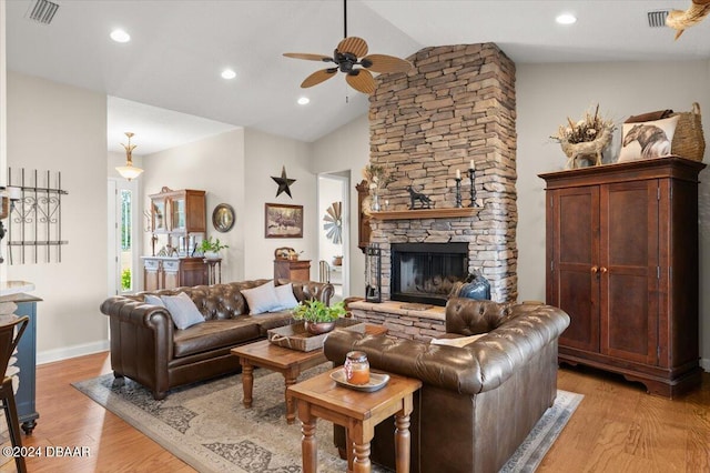 living room featuring ceiling fan, a fireplace, vaulted ceiling, and light hardwood / wood-style flooring