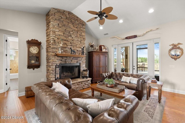 living room featuring ceiling fan, french doors, vaulted ceiling, a fireplace, and light wood-type flooring