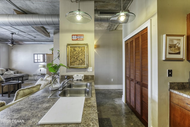 kitchen with a ceiling fan, baseboards, concrete floors, a sink, and open floor plan