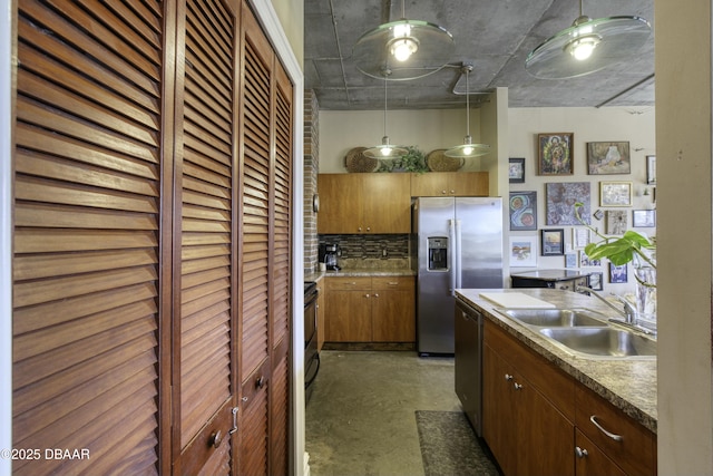 kitchen featuring concrete floors, decorative light fixtures, decorative backsplash, appliances with stainless steel finishes, and a sink