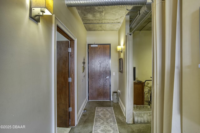 hallway with baseboards and concrete flooring