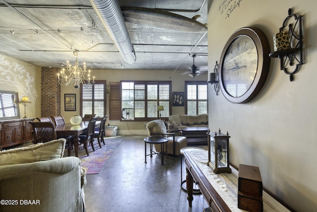 living area with baseboards, finished concrete floors, and ceiling fan with notable chandelier