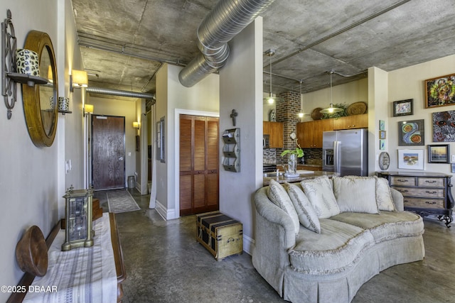 living room with baseboards, concrete floors, and a towering ceiling