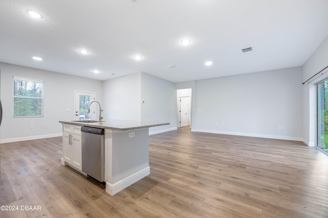 kitchen featuring white cabinets, light hardwood / wood-style floors, stainless steel dishwasher, and an island with sink