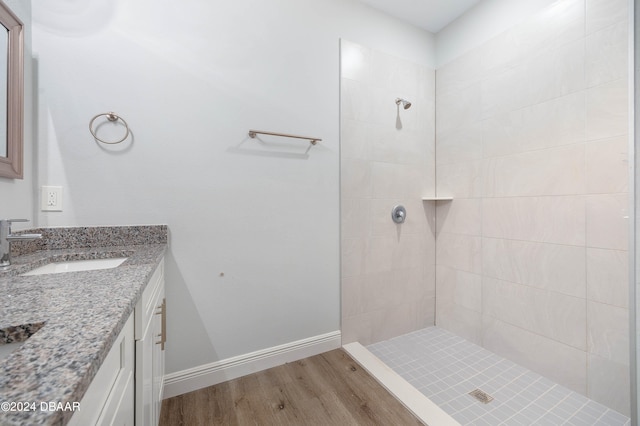 bathroom featuring wood-type flooring, vanity, and a tile shower