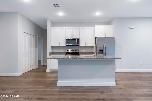 kitchen with stainless steel appliances, sink, an island with sink, white cabinets, and dark wood-type flooring