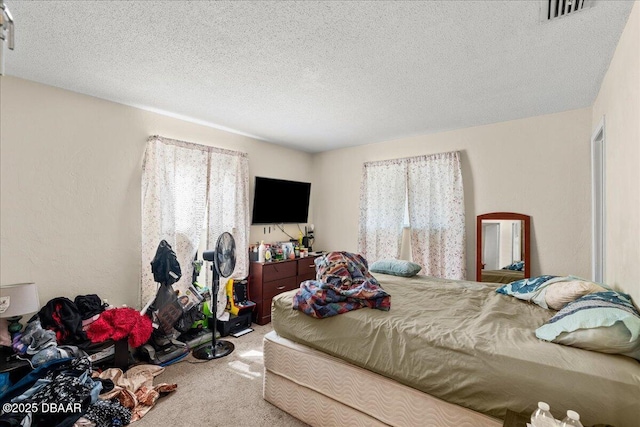 bedroom with a textured ceiling, multiple windows, visible vents, and carpet flooring