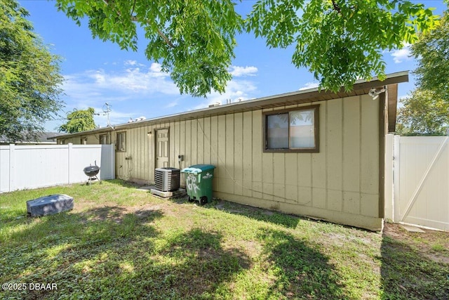 back of house with central air condition unit, fence private yard, a gate, and a yard